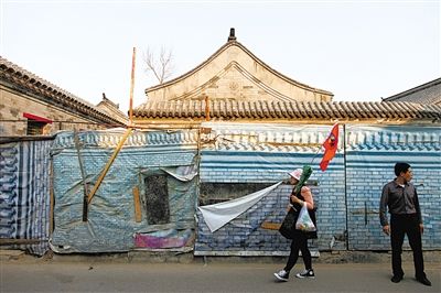 昨日，小石碑胡同，一位导游带着游客走过建筑围挡。西城区今年计划启动什刹海旧城保护示范项目。新京报记者