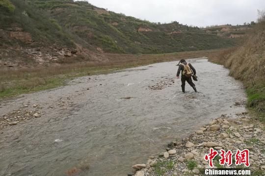 图为童金南教授趟水过河前往剖面。　田力 摄